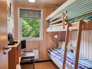 Ein gemütlicher Raum mit Etagenbett, Schreibtisch mit Computer, Fenster mit Blick ins Grüne und Heizkörper.