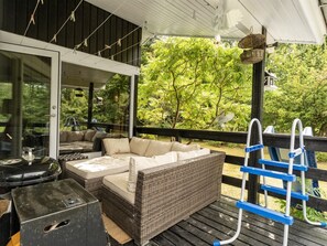 Eine Terrasse im Freien mit einem Korbsessel, einem Grill und einer blauen Leiter.