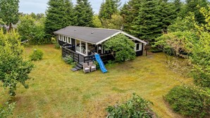 A cabin with a deck, a slide, and a fenced yard surrounded by trees. - "Tarvo" - 500m to the fjord by Interhome (Løgstør)