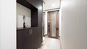 A hallway with a dark wooden cabinet, a door with vertical light strips, and a tiled floor.