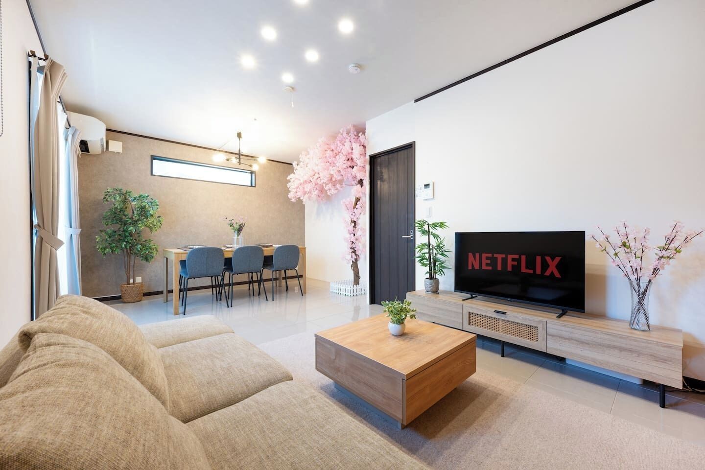 Un salon moderne comprenant un canapé, une table basse, un téléviseur et un coin repas avec des chaises et une table.