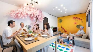 A dining area with a table set for a meal, surrounded by chairs, and a sofa in the background.