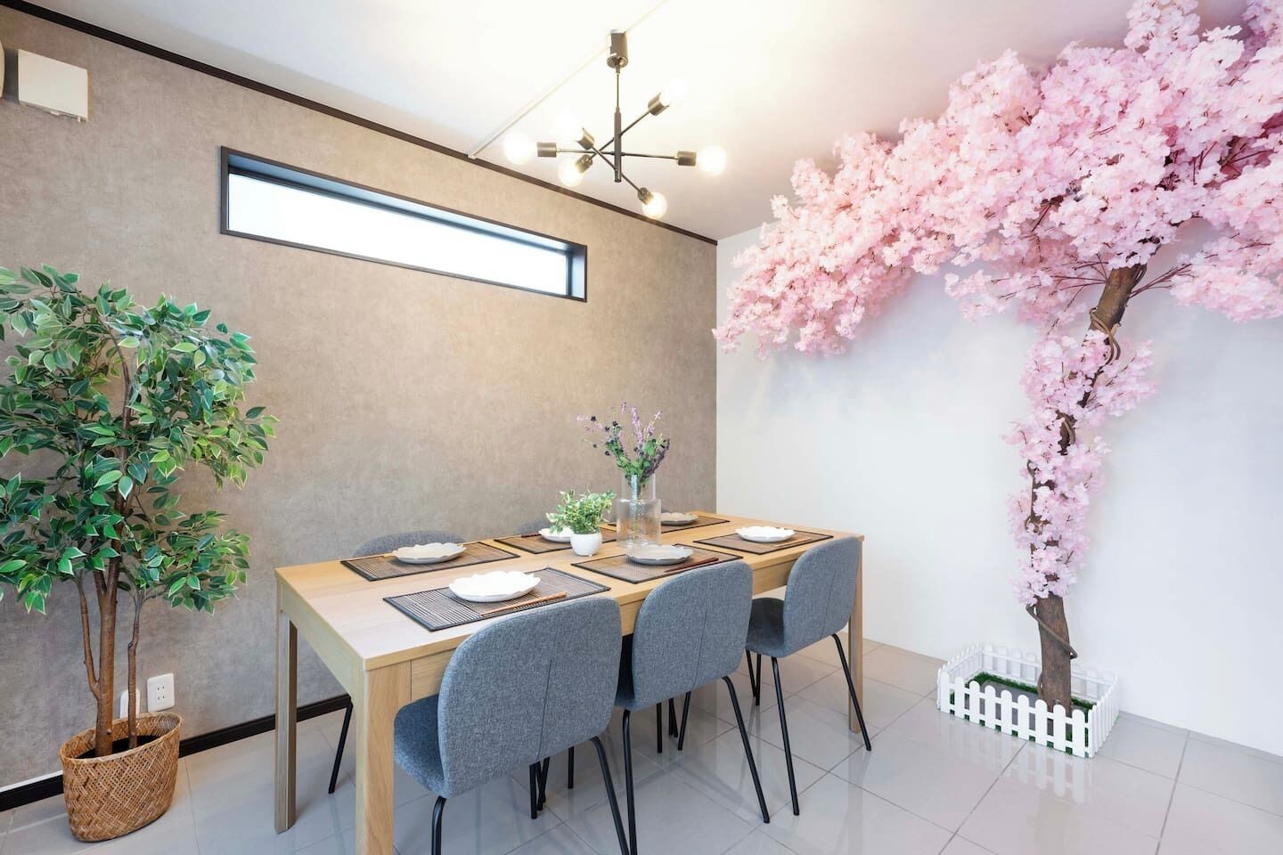 A dining area with a wooden table, grey chairs, and a decorative pink cherry blossom tree.