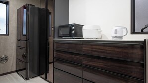 A modern kitchen with a built-in refrigerator, microwave, and kettle on the counter. - 87㎡House/4 min Station/Haneda straight limo bus/Near Disneyland/3 Bedrooms (Katsushika City)