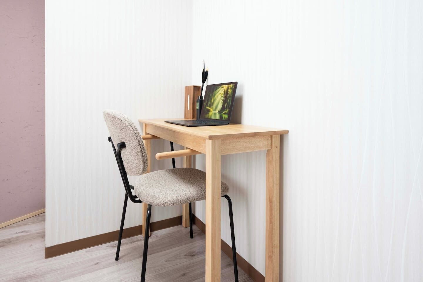 A corner workspace with a wooden desk, a chair, and a laptop.