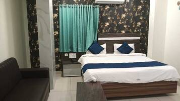 A bedroom with a bed, a nightstand, a sofa, and a window with curtains.