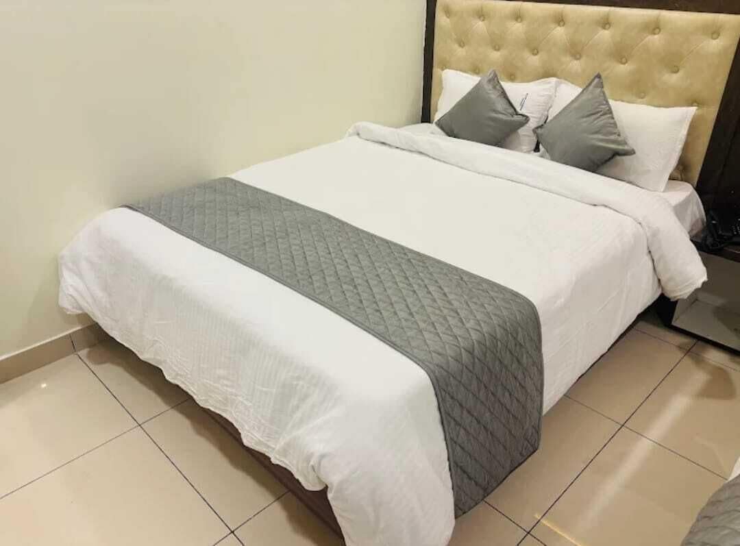 Una cama bien hecha con colcha acolchada y almohadas.