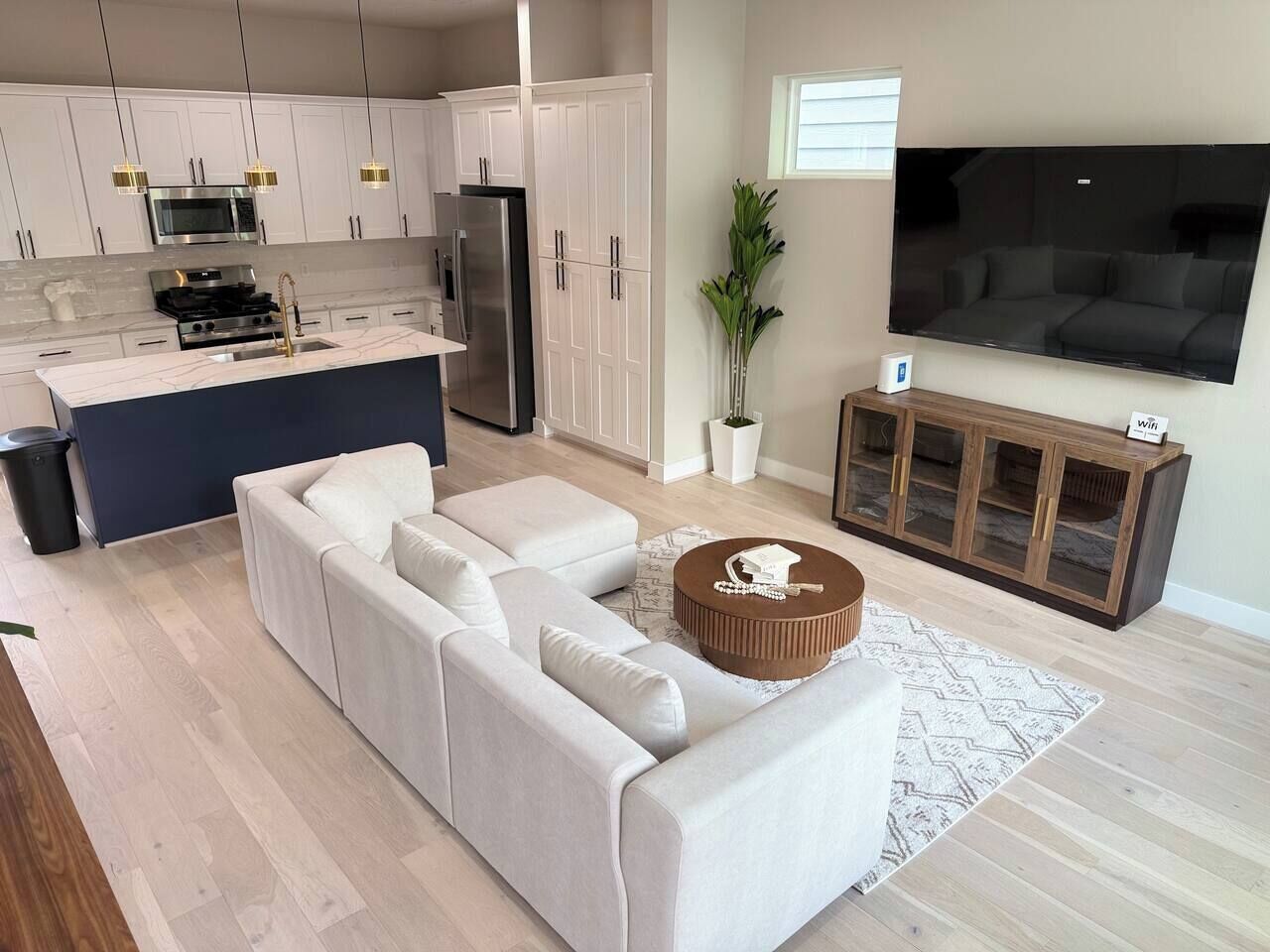 A modern kitchen with white cabinets, stainless steel appliances, and pendant lighting.