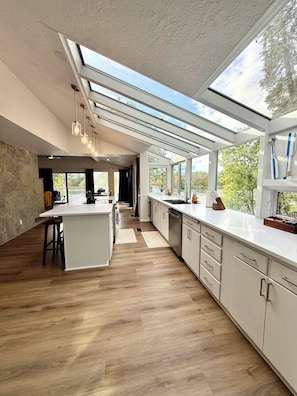 A modern kitchen with a central island, white cabinetry, and a skylight.