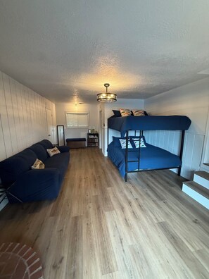 A compact room with a bunk bed, a sofa, a small table, and a ceiling light fixture. - Willamette Riverfront Estate - Wine County. Secluded on 2.5 acres w/Deck Views. (Salem)