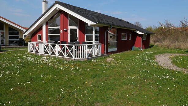 A red building with a white balcony, large windows, and a chimney. - Strandhaus mit Spa-bereich (Grossenbrode)