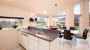 A modern kitchen with a large island, stainless steel sink, and black chairs. - Strandhaus mit Spa-bereich (Grossenbrode)