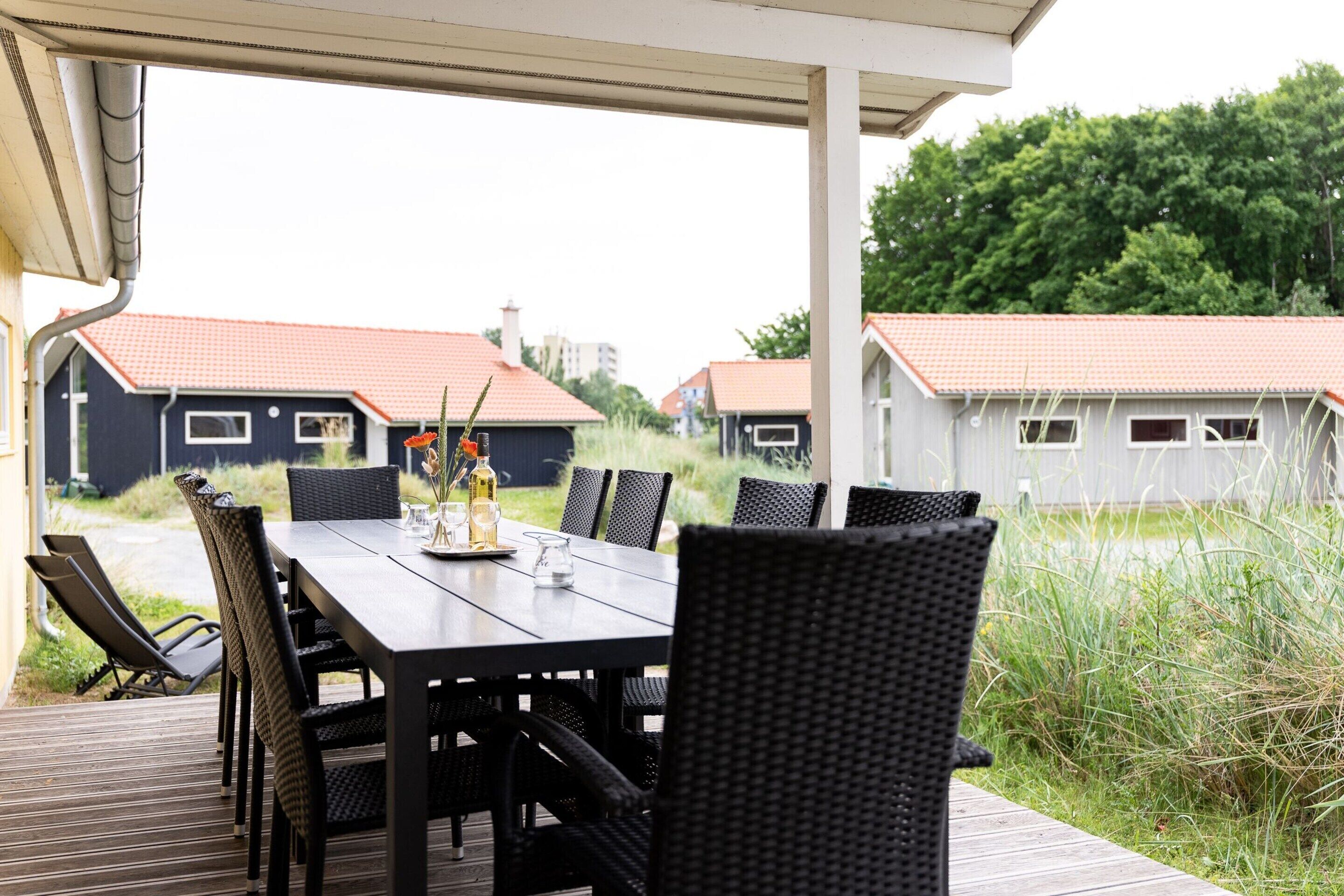 An outdoor dining area with a table and chairs, overlooking a residential neighborhood with houses.