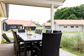 Ein Essbereich im Freien mit Tisch und Stühlen, mit Blick auf eine Wohngegend mit Häusern.