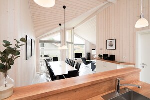A modern kitchen with a wooden countertop, a sink, and a dining area with a large table and chairs.