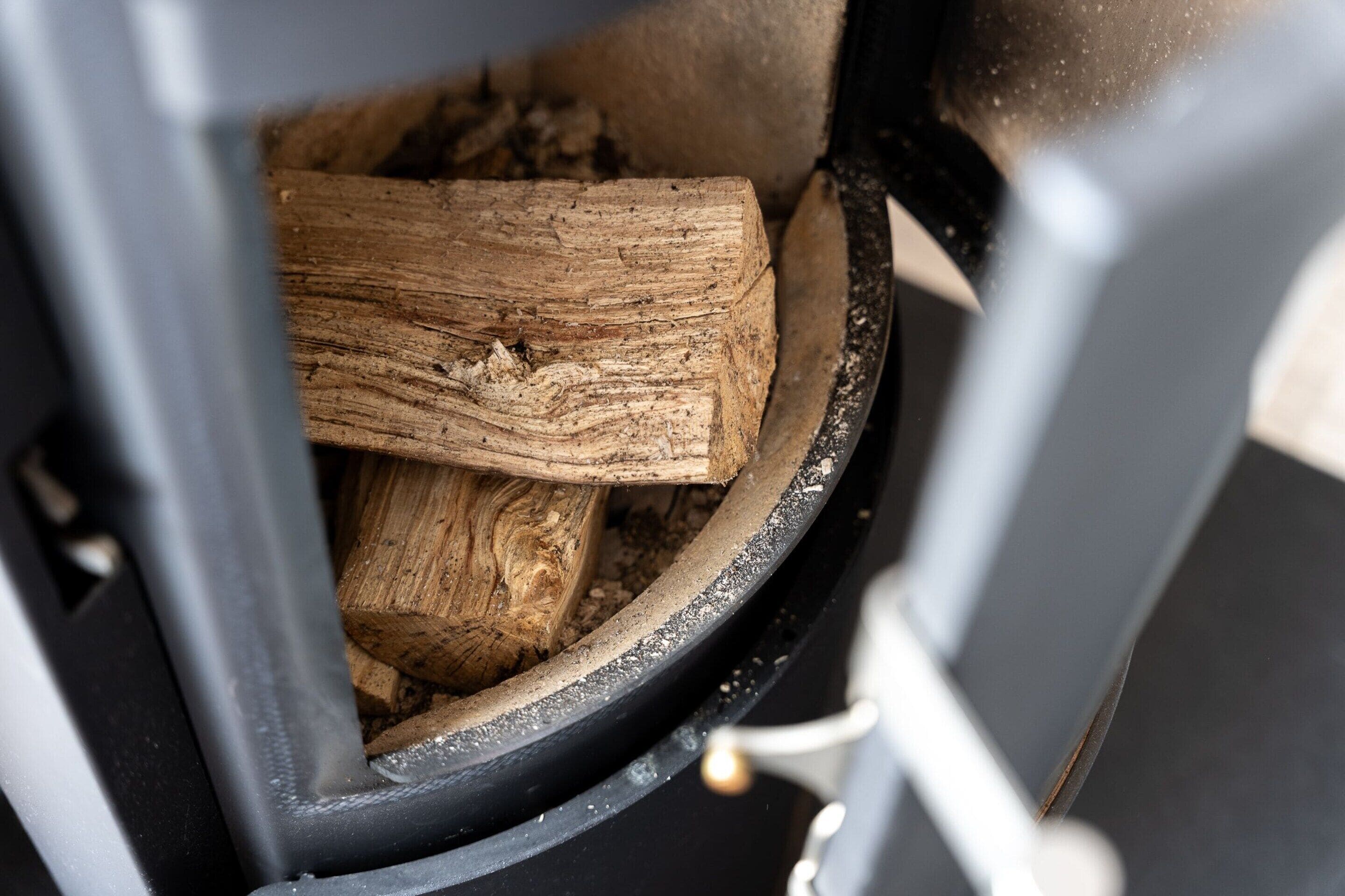 Un gros plan d’un poêle à bois avec des bûches à l’intérieur.