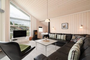 A modern living room with a large TV, a fireplace, a sofa, and a dining table.