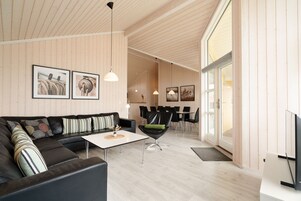 Ein modernes Wohnzimmer mit einer Eckcouch, einem Couchtisch und einem Essbereich mit Stühlen und einem Tisch.