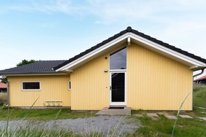 A yellow single-story building with a black roof, a small window, and a door.