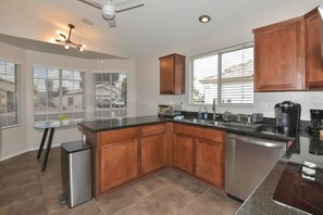 A modern kitchen with a central island, stainless steel appliances, and wooden cabinetry. - Waterfront 3-bedroom House in Lake Community with Mountain View (Glendale)
