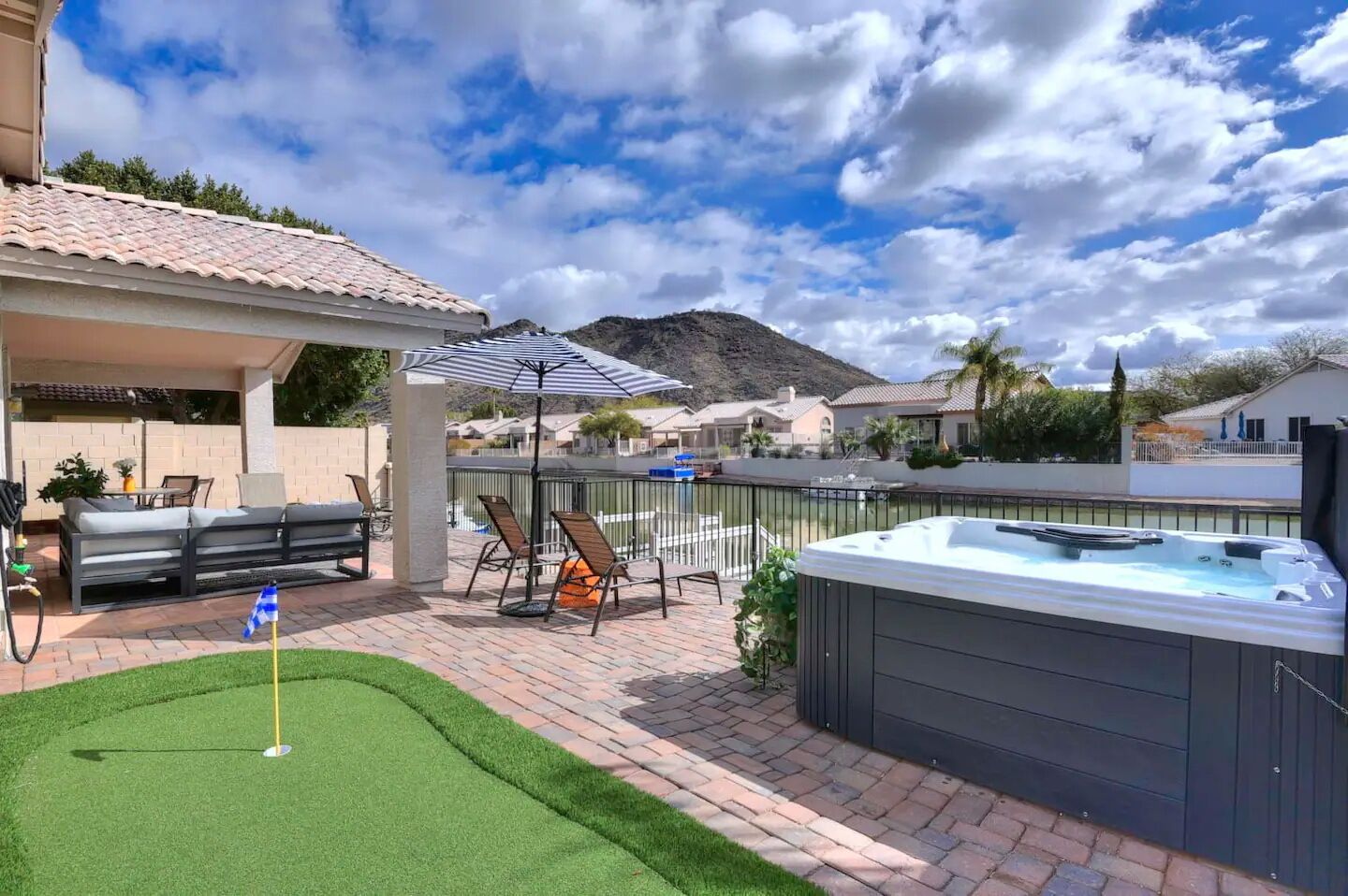 A patio with a hot tub, outdoor seating, and a view of a mountain.