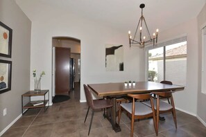 A dining area with a large table, chairs, a chandelier, and artwork on the walls. - Waterfront 3-bedroom House in Lake Community with Mountain View (Glendale)