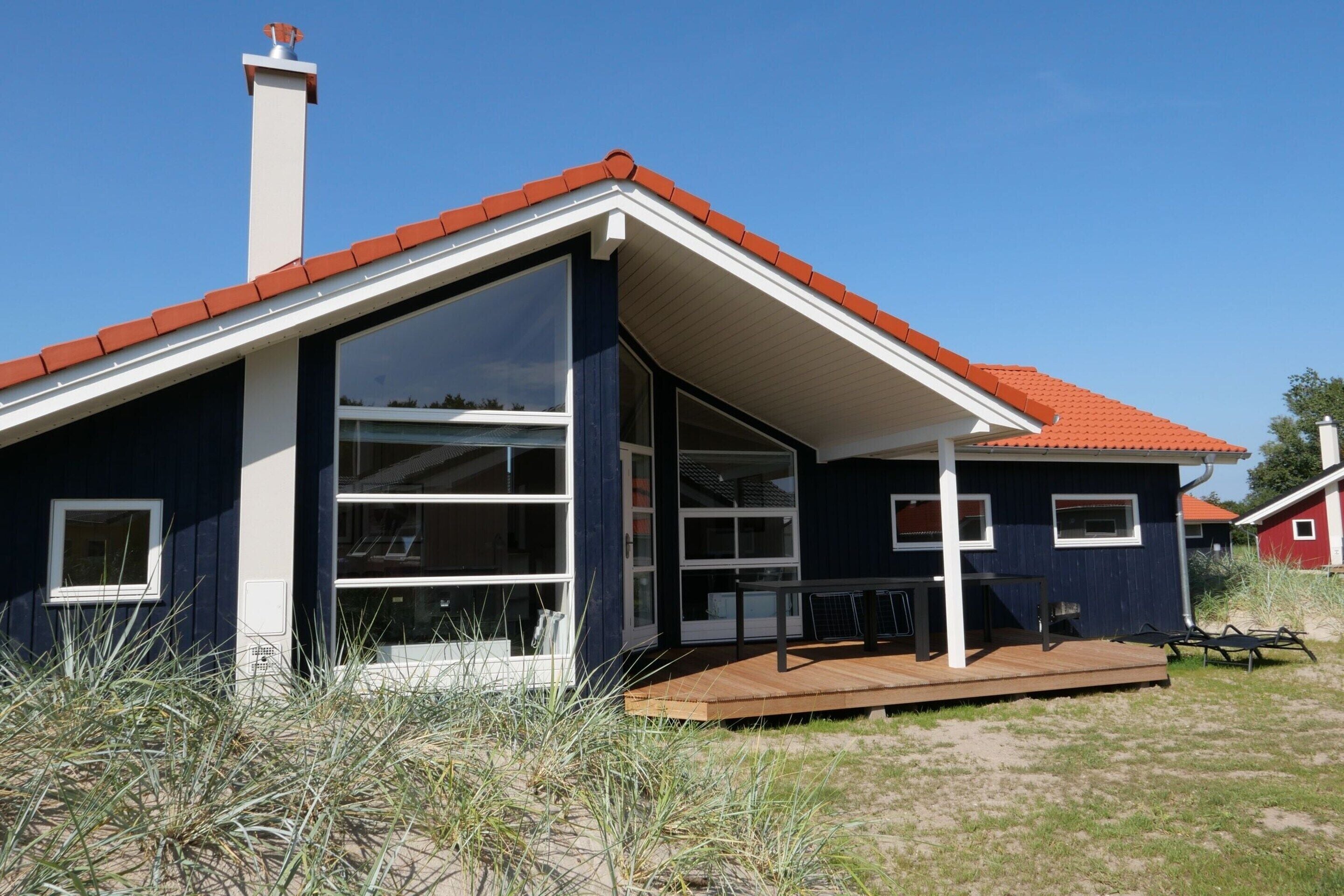 Et moderne hus med skrå tag, store vinduer og en træterrasse.