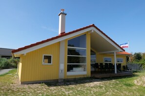 Ein gelbes Gebäude mit rotem Dach, Schornstein und einer Flagge.