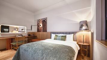 Quarto de hotel com cama, mesas de cabeceira, escrivaninha, cadeira, abajur e um quadro na parede.