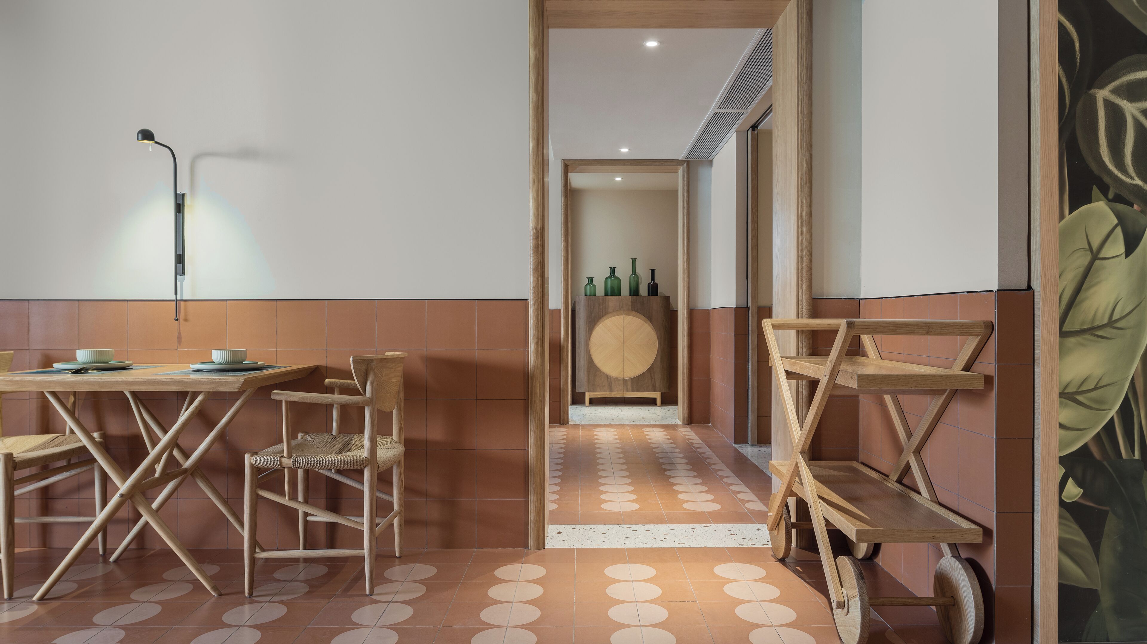 Un comedor moderno con una mesa de madera, sillas y una lámpara fijada a la pared.