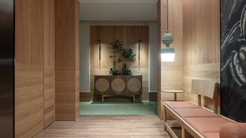 A modern interior with wooden paneling, a central console table, a bench, and a hanging light fixture.