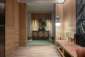 Un interior moderno con paneles de madera, una consola central, un banco y una lámpara colgante.