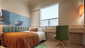 Habitación de hotel con cama, escritorio, silla, ventana y un mural en la pared.