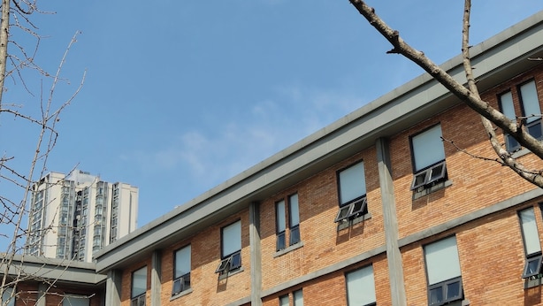 Un edificio de varios pisos con fachada de ladrillo y numerosas ventanas, algunas con toldos.