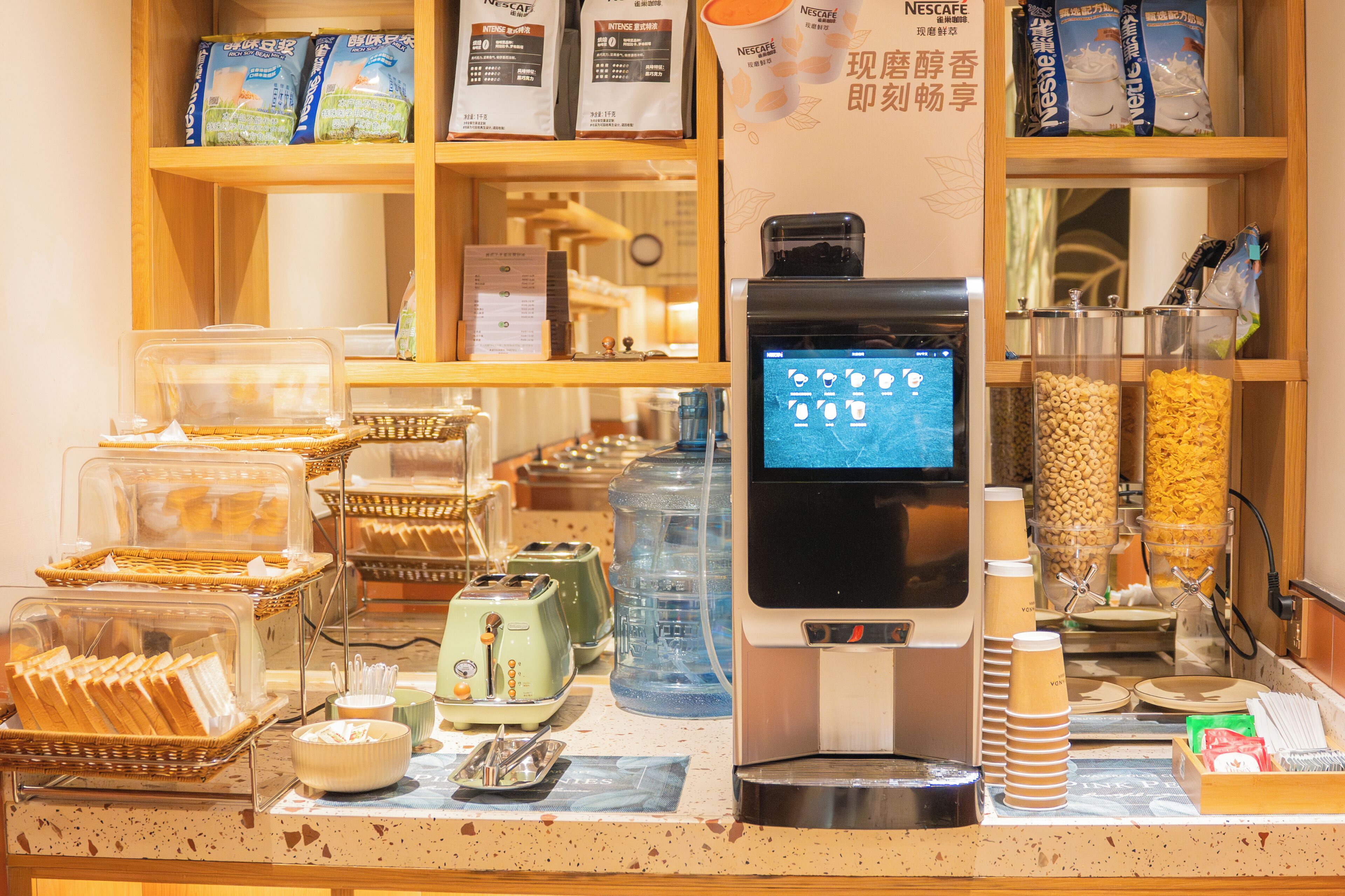 Bancada de café com máquina de café, um quadro de cardápio e diversos alimentos como pão e cereais.