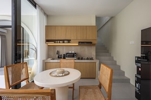A modern kitchen with wooden cabinets, a round dining table, and a built-in stove.
