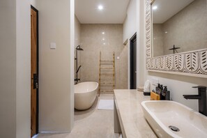 Un baño moderno con una bañera independiente, un espejo grande y un tocador con lavabo.