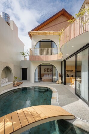 Ein modernes Haus mit Schwimmbad, Balkon und Essbereich.