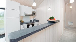 A modern kitchen with white cabinetry, a black countertop, and a built-in oven. - Skandinavisches Haus fur 10 (Grossenbrode)
