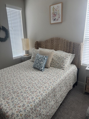 A bedroom with a bed, a wall-mounted lamp, a decorative wall piece, and a window with blinds. - Fully Furnished 3-bedroom house in San Antonio with cool AC (San Antonio)