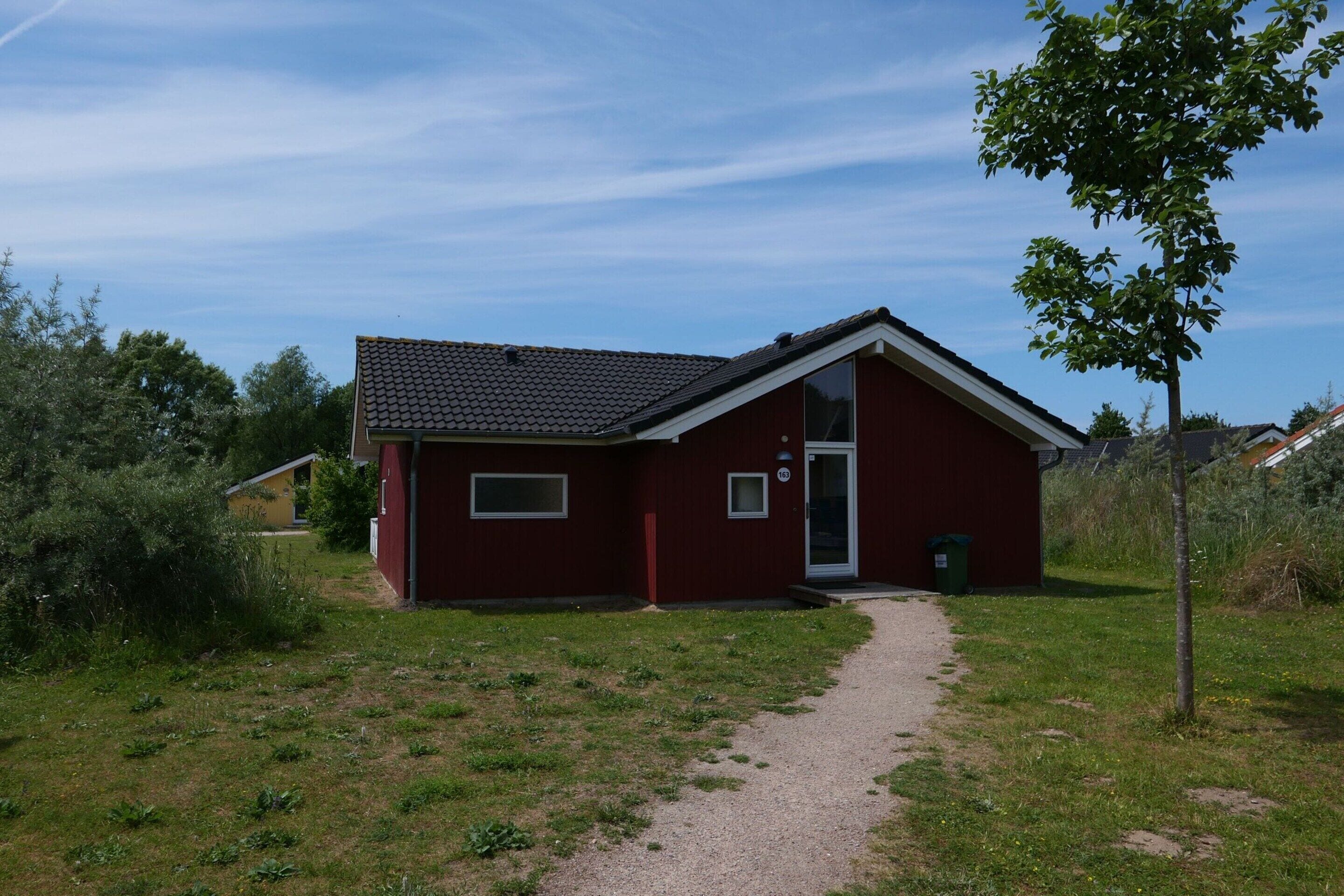 A red single-story building with a tiled roof, a small front porch, and a paved driveway leading to the entrance.
