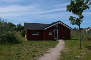 A red single-story building with a tiled roof, a small front porch, and a paved driveway leading to the entrance.