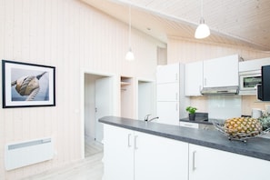 Una cocina moderna con muebles blancos, un horno de acero inoxidable y una encimera con una piña.
