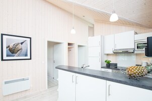 A modern kitchen with white cabinetry, a stainless steel oven, and a countertop with a pineapple.