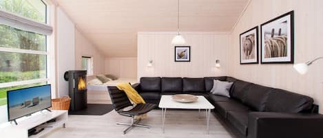 Una sala de estar moderna con un sofá modular, un televisor, una chimenea y ventanas amplias.