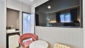 Habitación de hotel con cama, una mesita redonda, una silla, televisor y ventana.