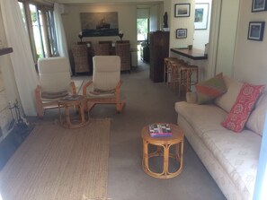 A living room with a sofa, two rocking chairs, a coffee table, and a dining area with a table and chairs. - COSY PORTSEA COTTAGE (Melbourne)