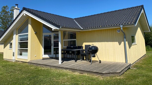 A house with a covered patio, a barbecue grill, and a number 12 sign on the wall. - Haus mit Zwei Flugeln fur Acht Personen (Grossenbrode)