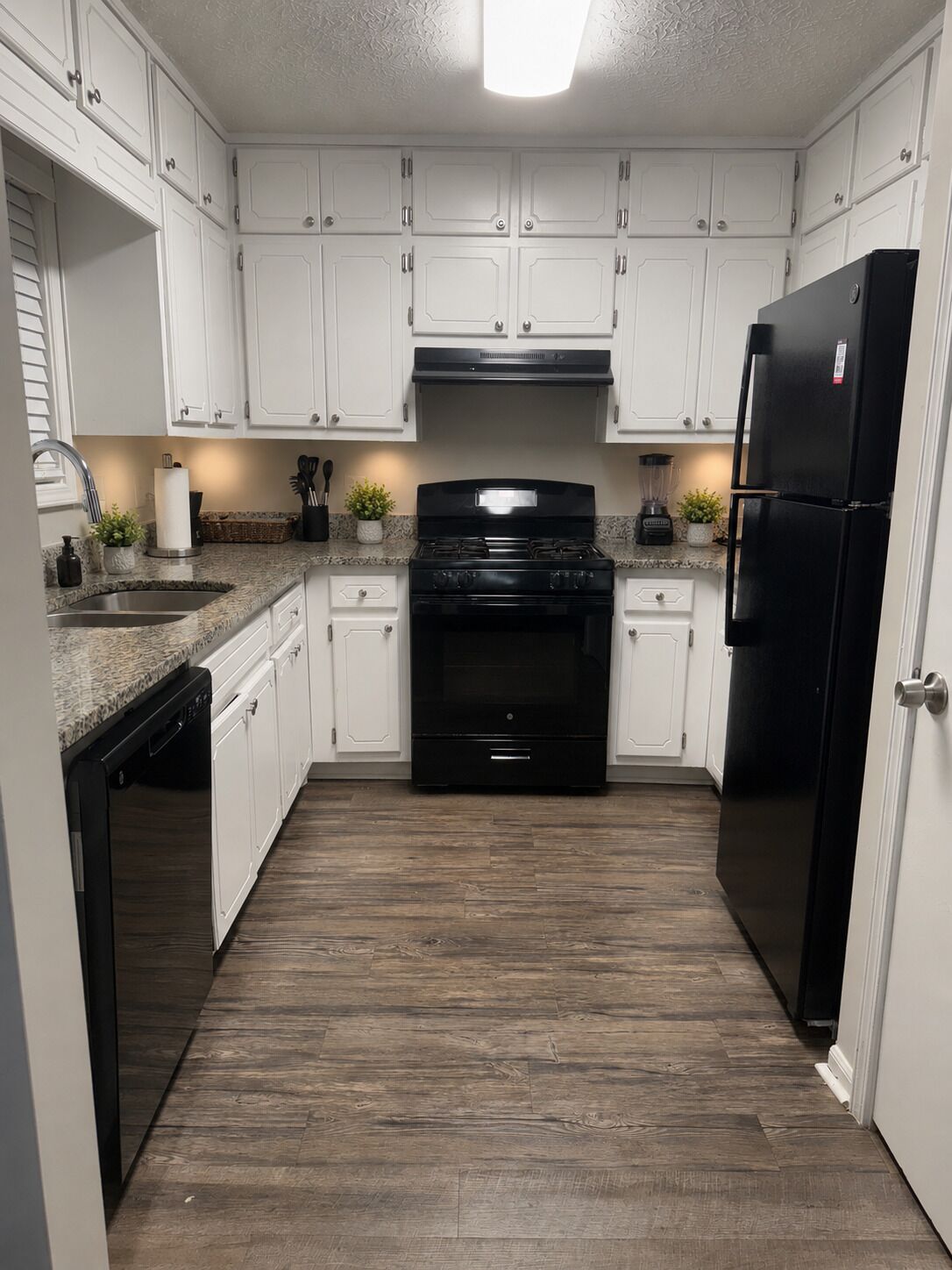 A kitchen with white cabinets, a black stove, and a black refrigerator.