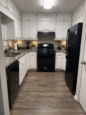 A kitchen with white cabinets, a black stove, and a black refrigerator. - 3-bedroom house in Atlanta 13min from Airport (Ellenwood)